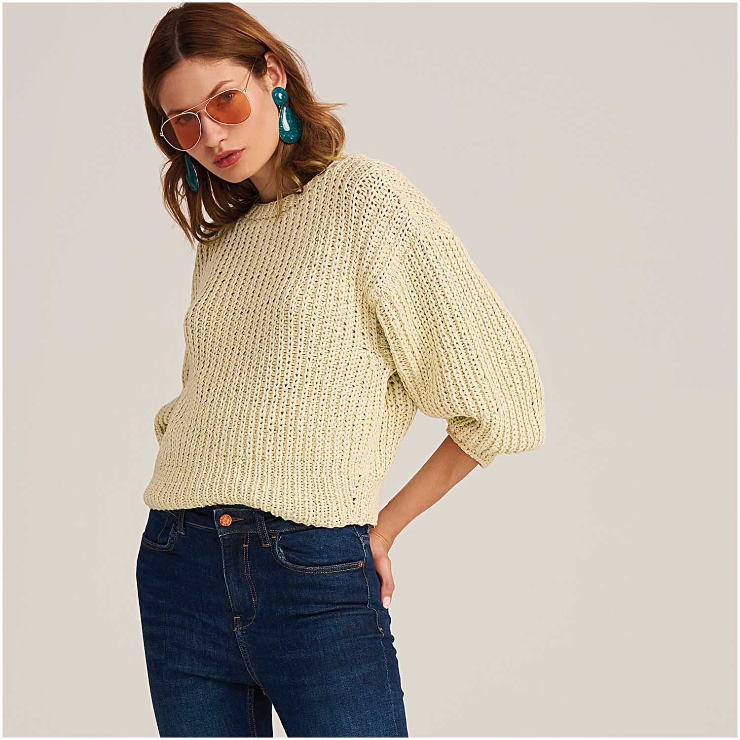 Fashion Cotton Ribbon Chunky: Frau trägt gestrickten Pullover in Pastellgelb, kombiniert mit blauer Jeans.