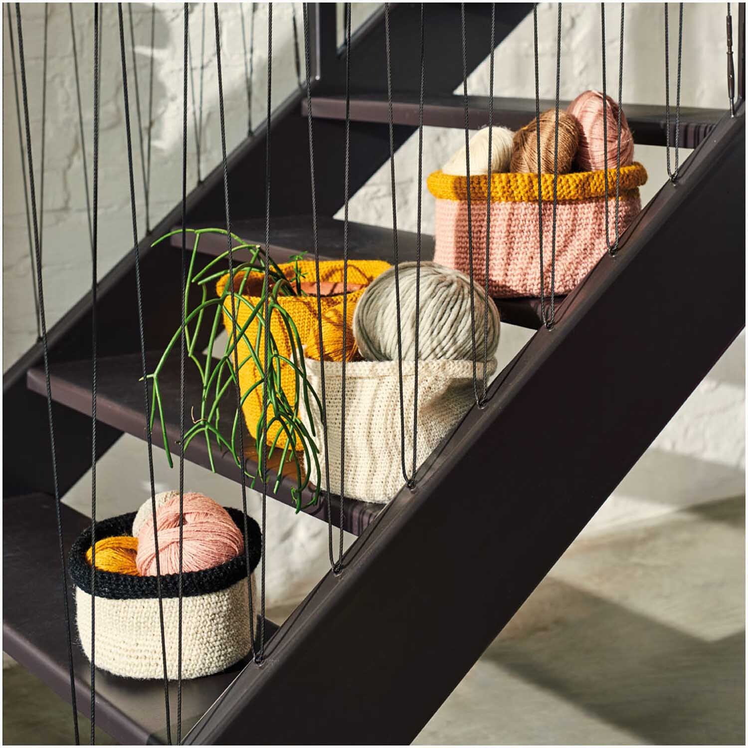 Creative Natur: Bunte Strickkörbe mit Rico Design Garn auf Treppe. Enthält Pflanzen und Wolle in verschiedenen Farben.