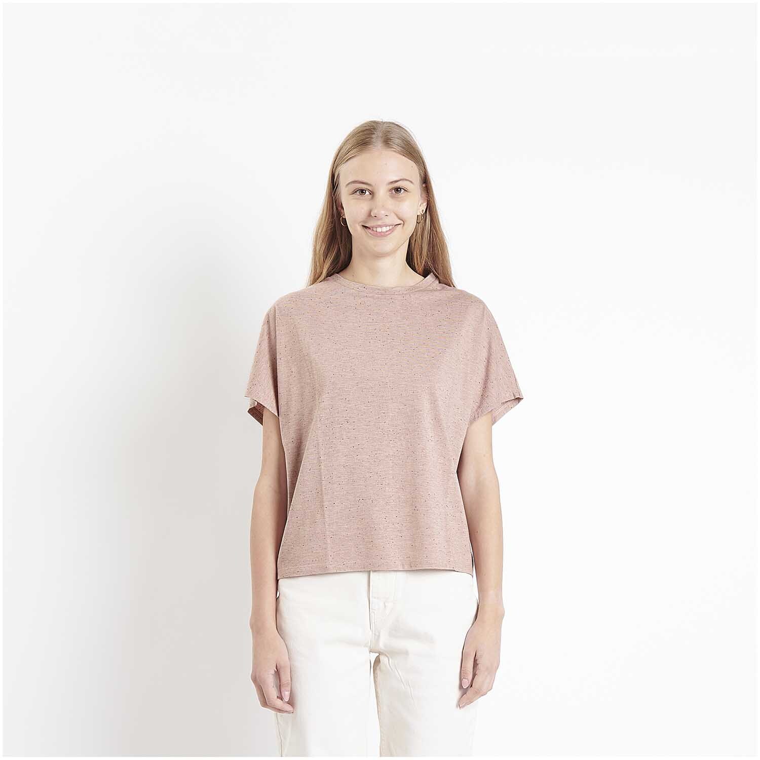Meterware Jersey Flocken Puder: Frau trägt ein puderfarbenes T-Shirt von Rico Design, stehend vor weißem Hintergrund.