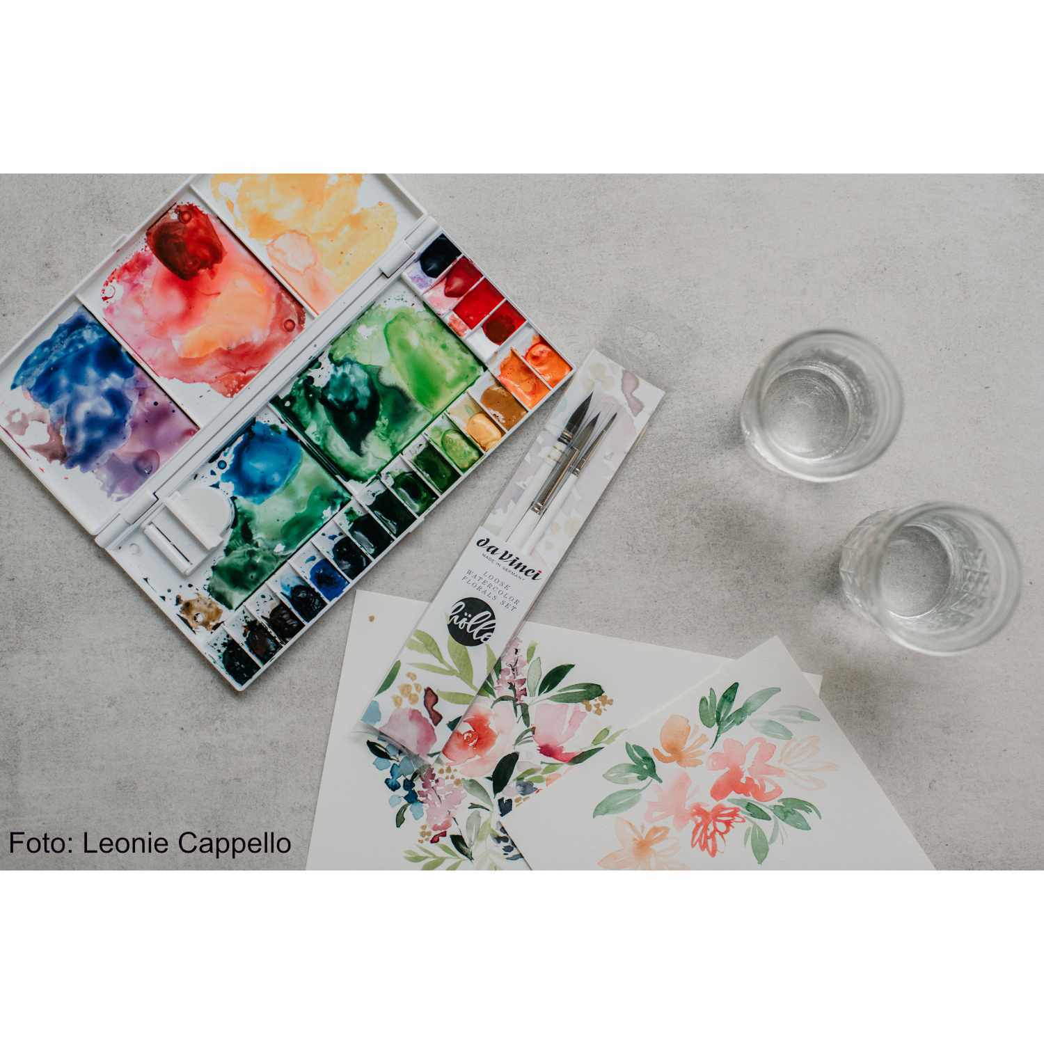 da Vinci Pinsel-Set Loose Watercolor Florals: Aquarellfarben und Pinsel auf Tisch mit floralen Malereien. Ideal für kreative Kunstprojekte.