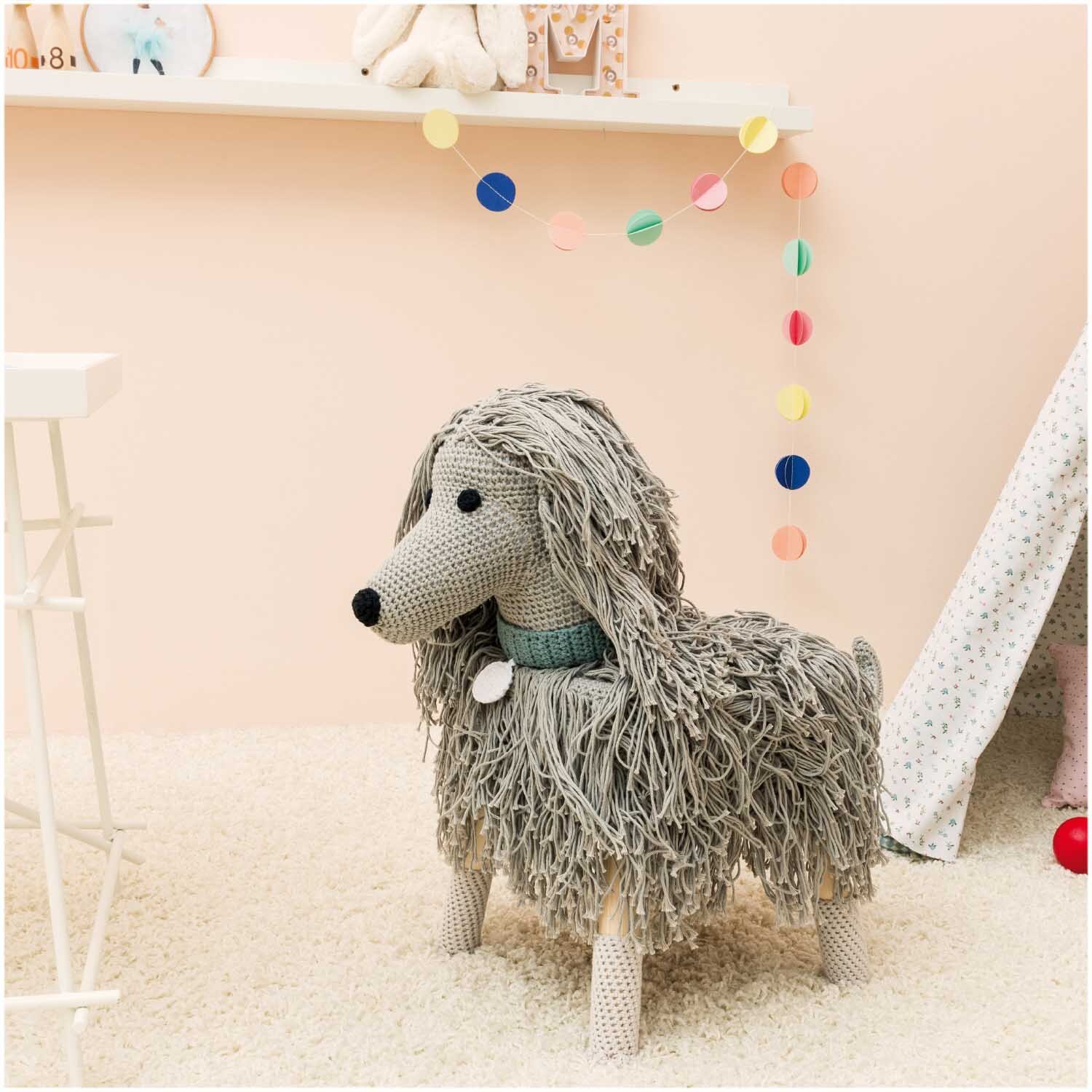 Creative Cotton aran: Handgestrickter Hund aus Rico Design Wolle, dekorativ im Kinderzimmer platziert.