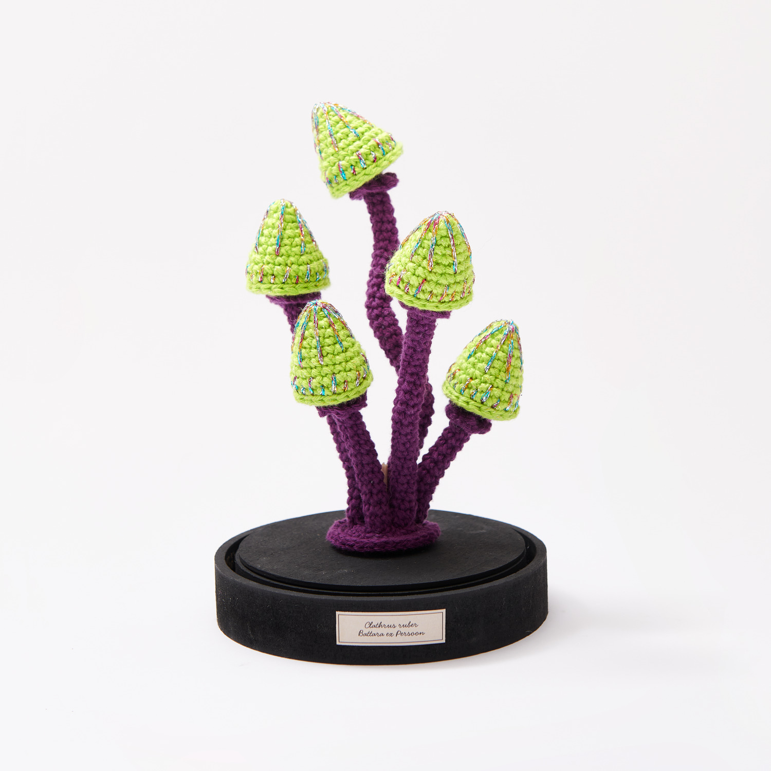 Creative Ricorumi dk: Gehäkelte, pilzförmige Figuren in Lila und Grün auf schwarzem Sockel, ideal für kreative Projekte.