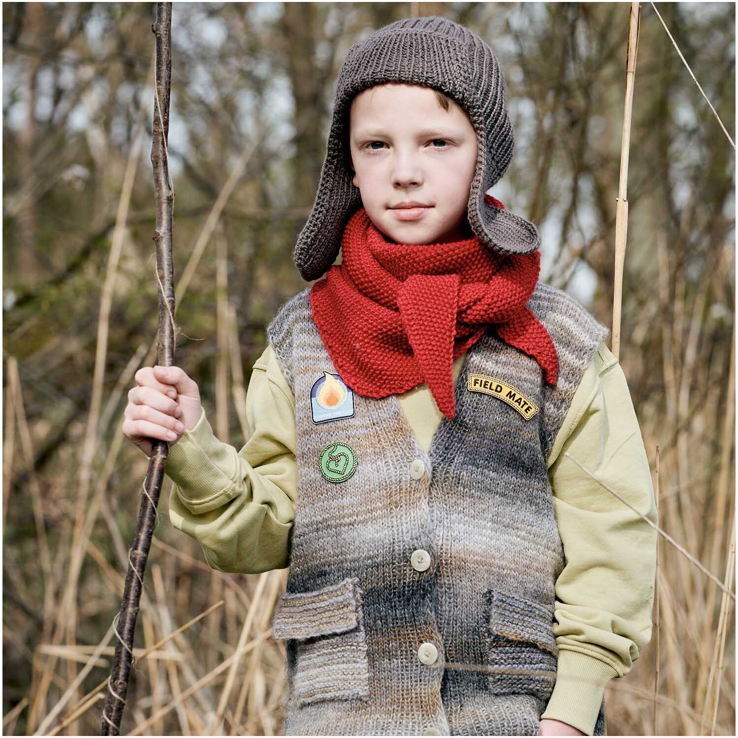Patches Pfadfinder Bär zum Aufbügeln: Kind mit gestrickter Mütze und Schal, trägt Weste mit Pfadfinder-Patches im Freien.