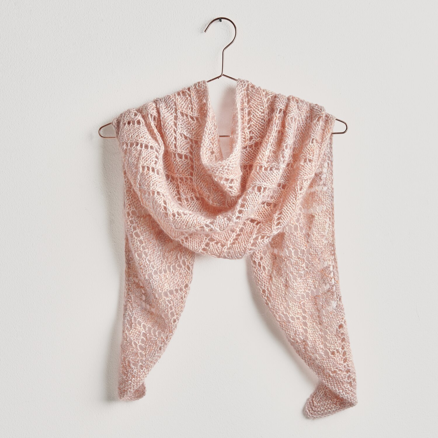 Strickset Dreieckstuch Modell 28 aus Lovewool No. 20: Zartrosa Tuch aus Baumwolle-Merino-Mischung, elegant drapiert auf einem Kleiderbügel.