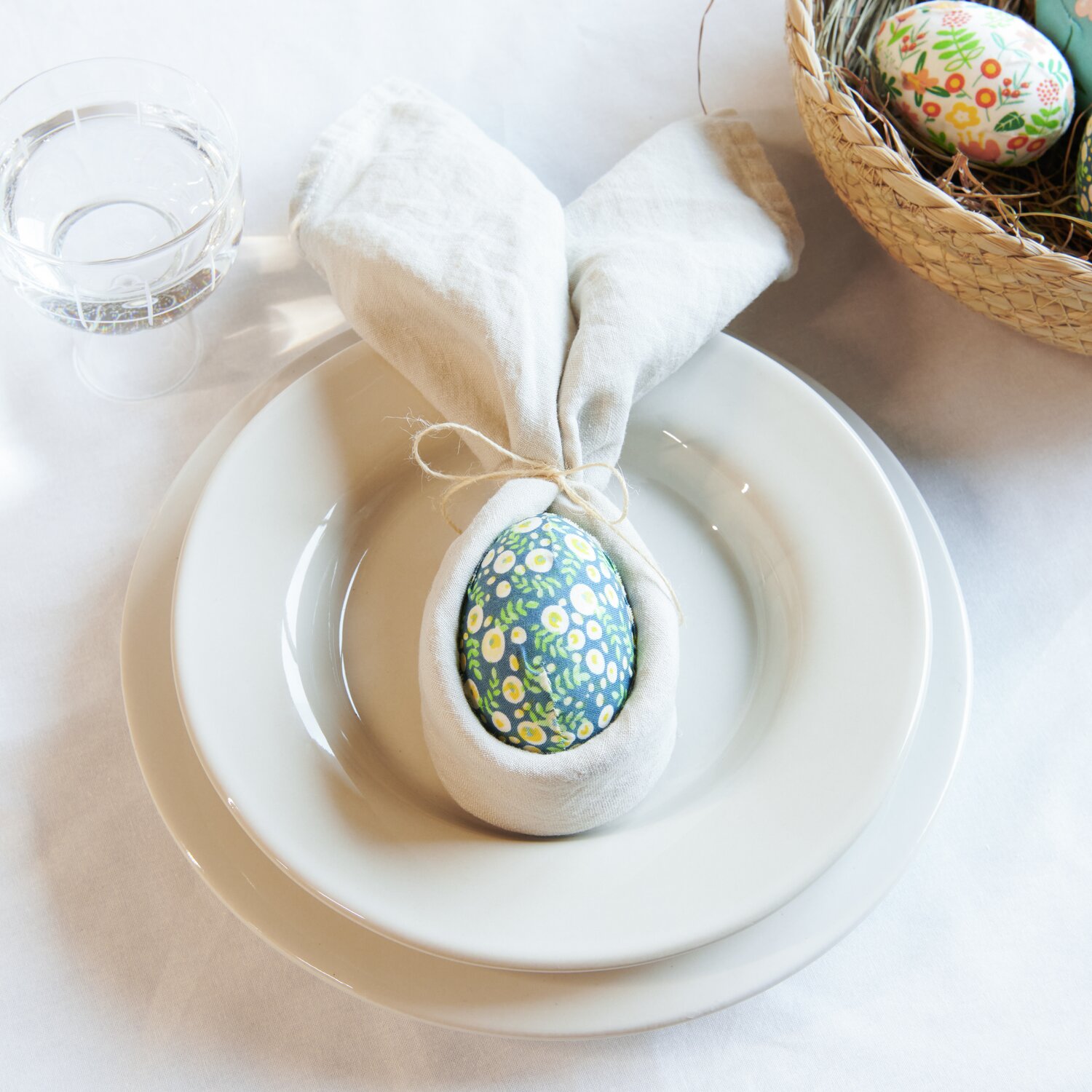 Eier Blumendesign 7cm: Ein dekoratives Ei mit Blumenmuster auf einem Teller, umgeben von Stoffserviette. Ideal für festliche Tischdekoration.