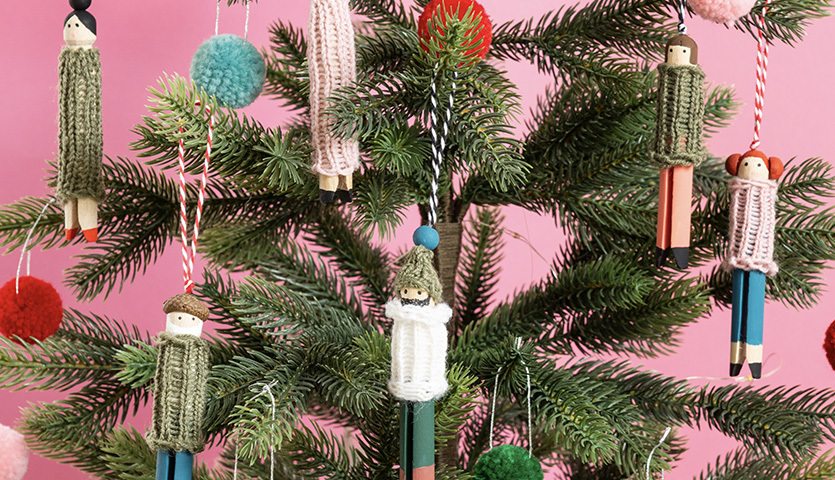 Bastelanleitung Baumschmuck aus Wäscheklammern: Handgefertigte Figuren an einem Tannenbaum mit bunten Pompons.