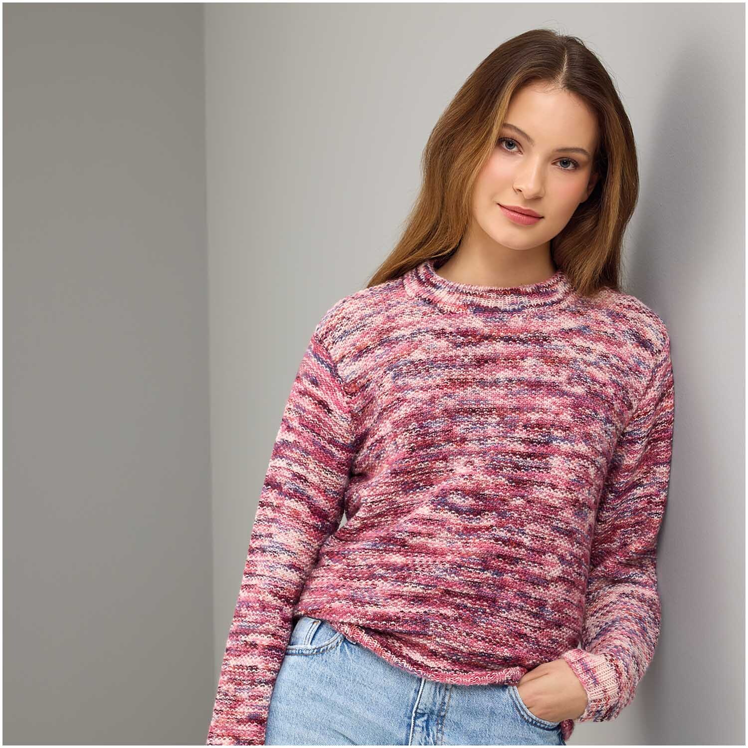 Strickset Pullover Modell 17: Frau trägt einen mehrfarbigen Pullover in Rosa- und Rottönen, lässig kombiniert mit Jeans.