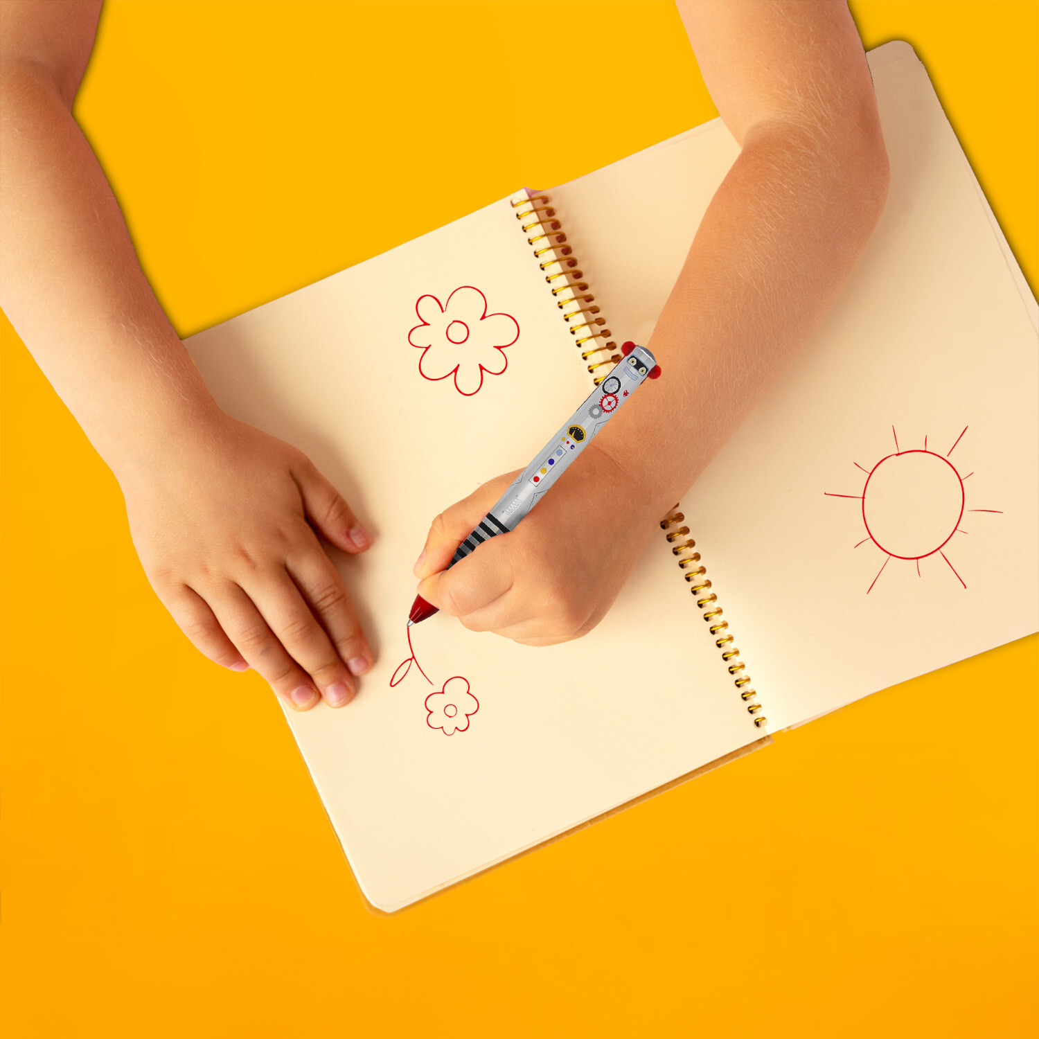 Zweifarbiger Kugelschreiber Click&Clack: Kind malt mit Legami-Stift auf Notizbuch, gelber Hintergrund.