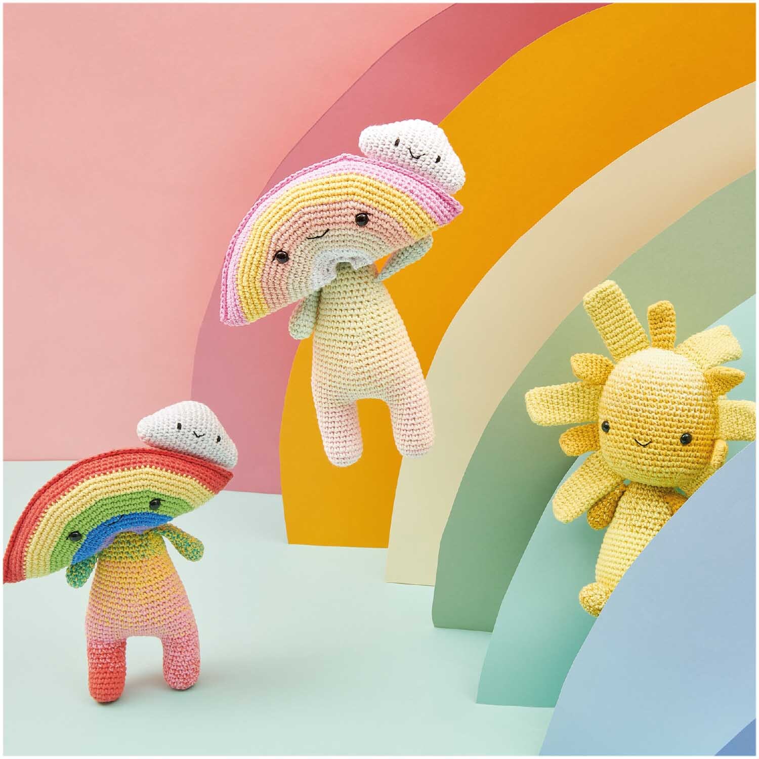 Ricorumi Spin Spin dk: Bunte gehäkelte Figuren vor einem Regenbogenhintergrund, ideal für kreative Projekte.