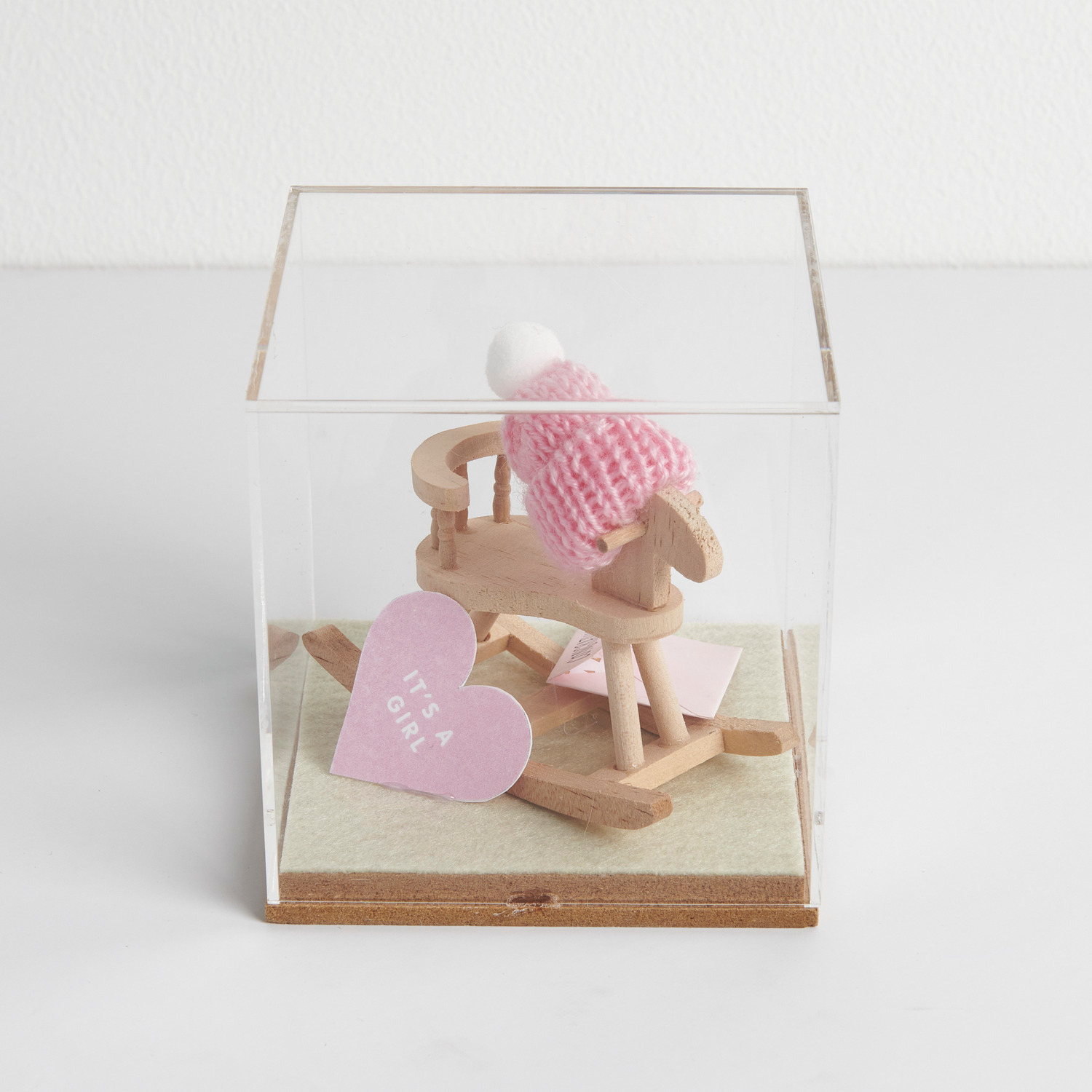 Figurico Dekohaube Würfel zeigt ein Holzschaukelpferd mit rosa Mütze und Herz mit "It's a Girl". Ideal als Geschenk zur Geburt.