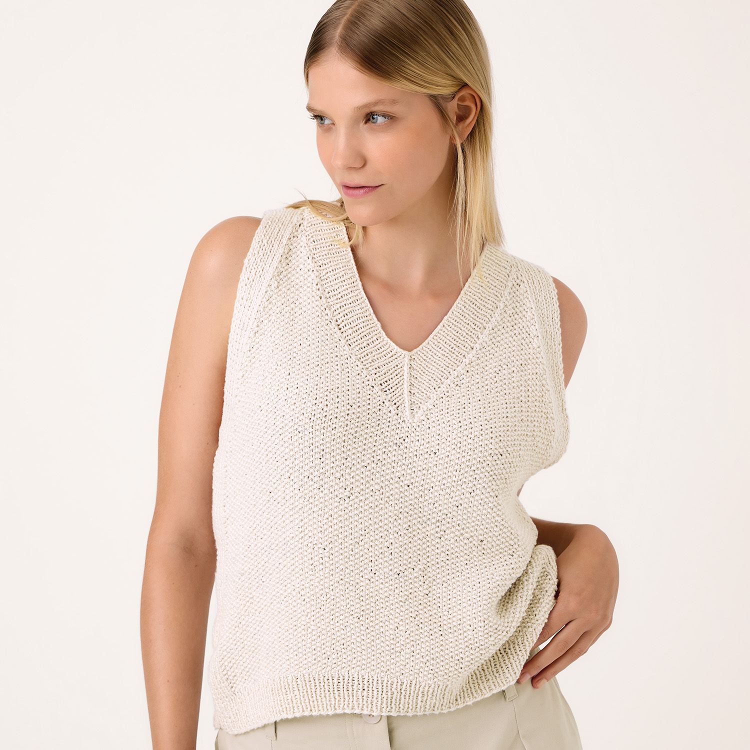 Strickanleitung Top aus Luxury Organic Cotton Silk dk: Frau trägt ärmelloses, cremefarbenes Stricktop mit V-Ausschnitt.
