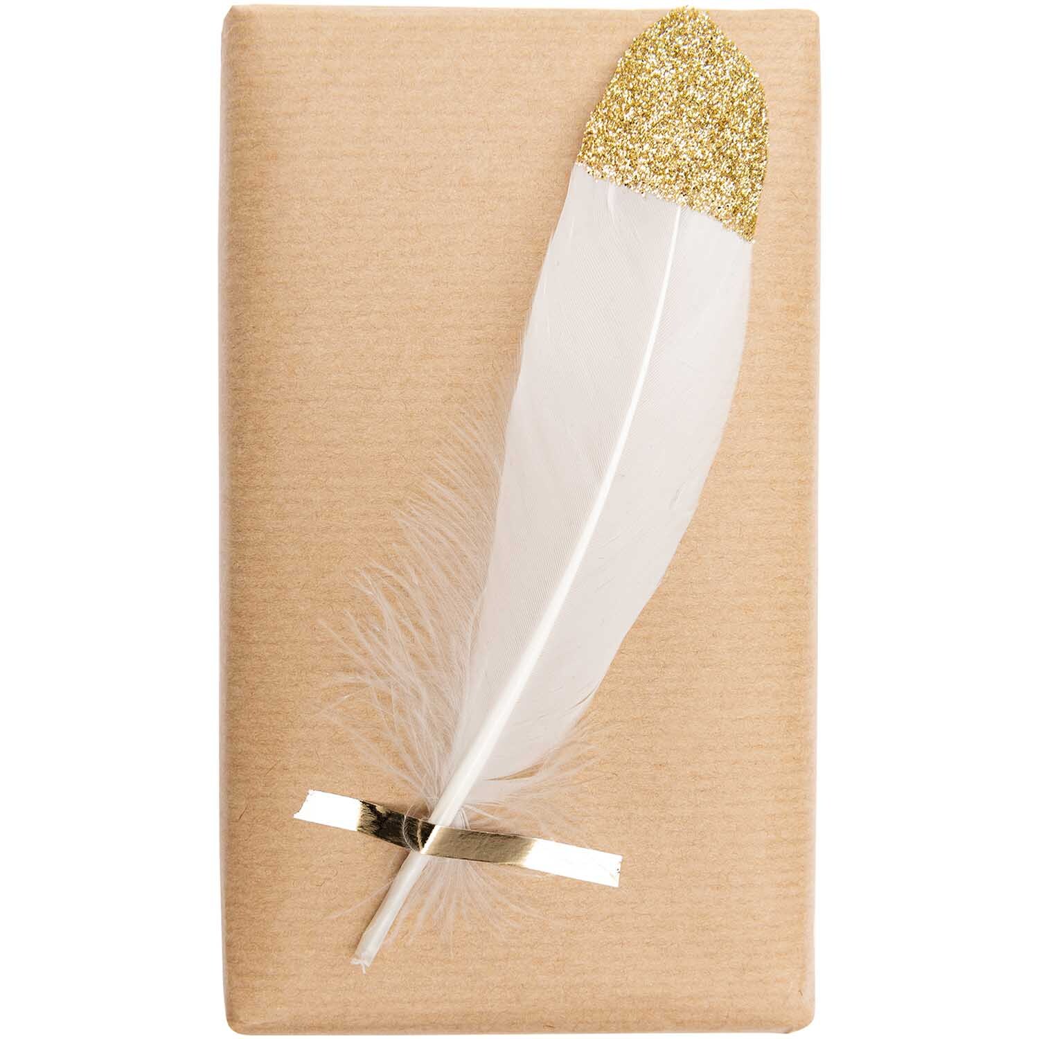 Federn ca. 18cm 6 Stück: Eine weiße Feder mit goldener Spitze auf braunem Hintergrund, ideal für kreative Dekorationen.