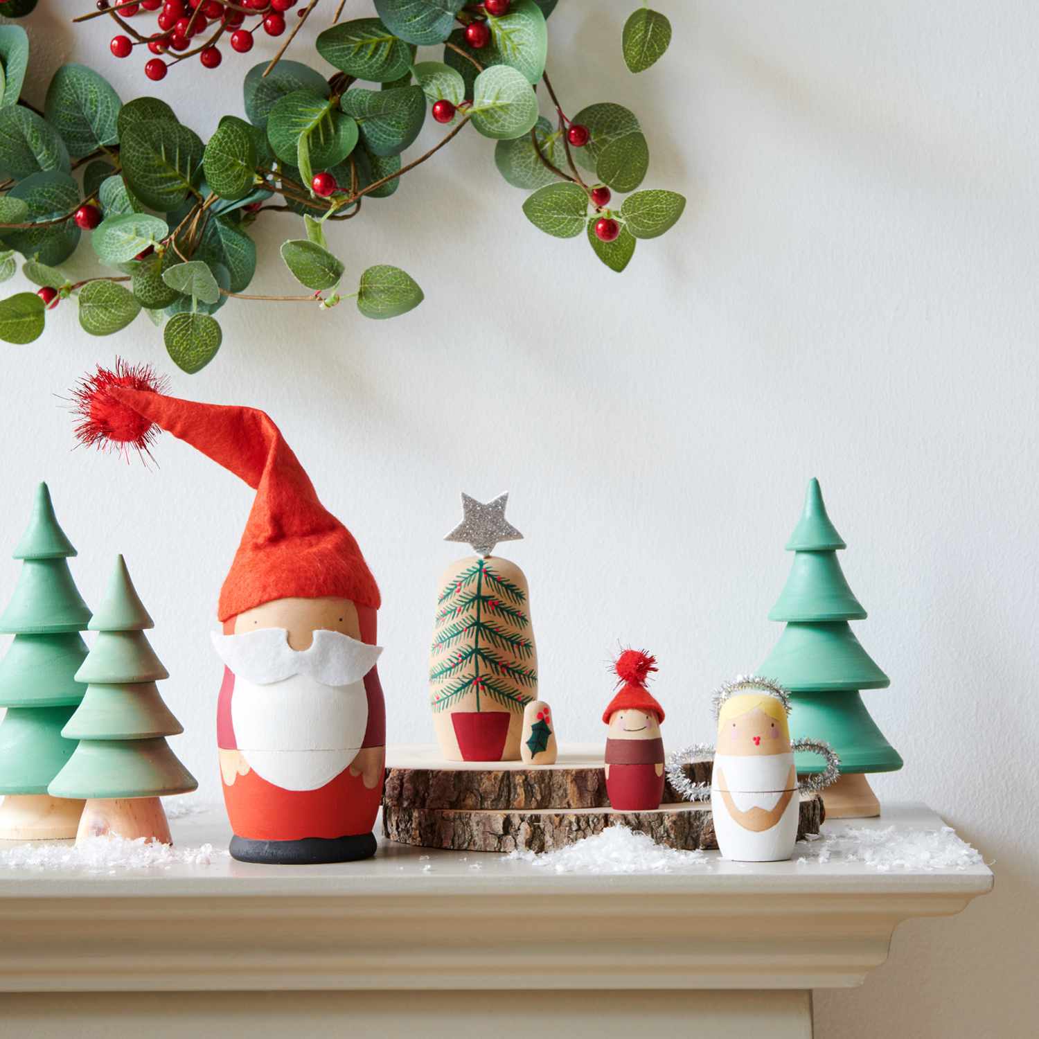 Bastelanleitung weihnachtliche Matroschka-Puppen: Festliche Puppen in Weihnachtsdeko mit Tannenbäumen und Kranz aus roten Beeren und grünen Blättern.