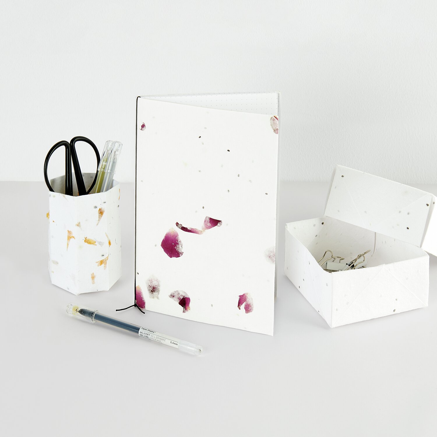 Paper Poetry Bastelbogen Baumwollpapier mit Rosenblüten, weiß, auf einem Tisch mit Stiften und Schere. Ideal für kreative Projekte.