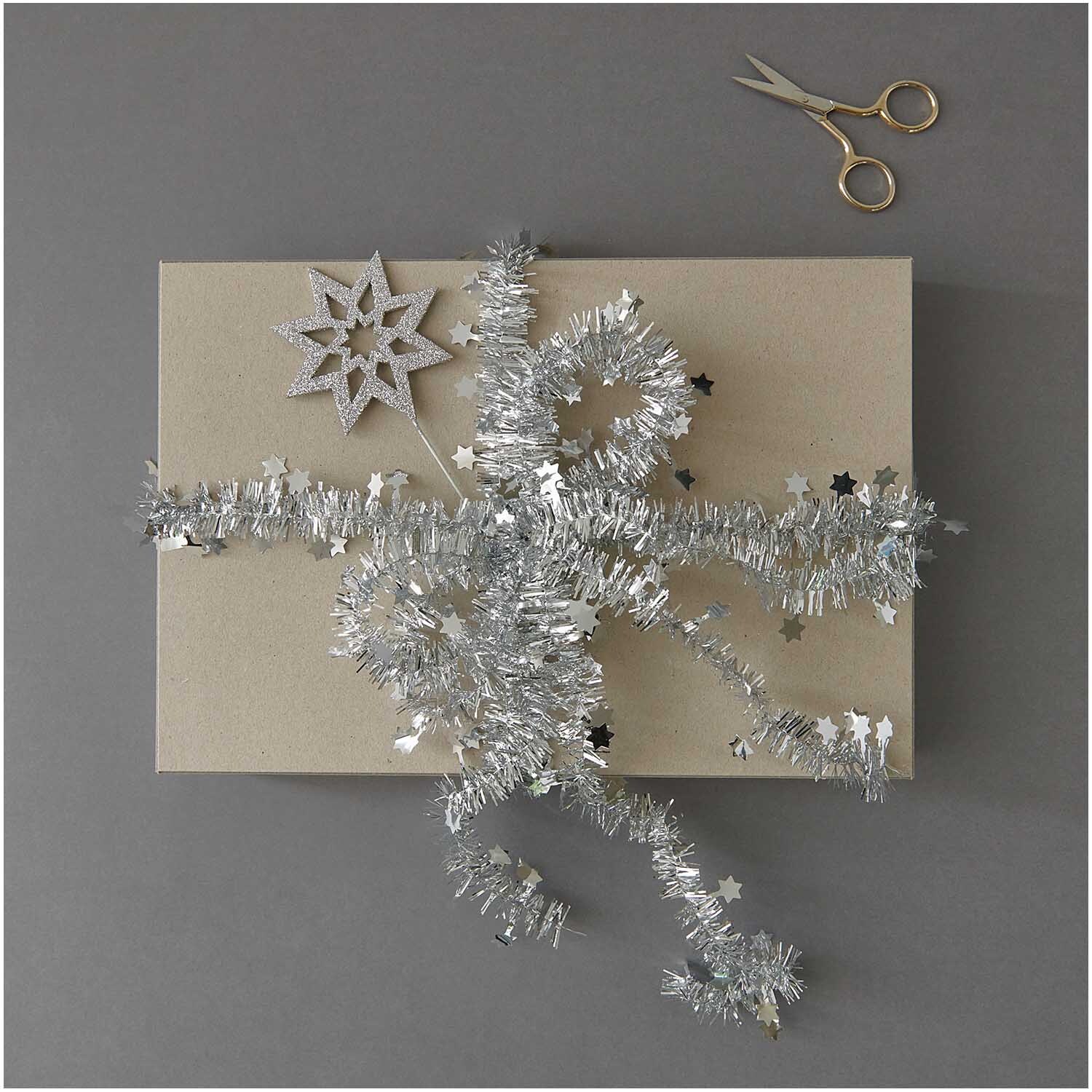 Glitter-Picker Stern 27x5cm von Rico Design auf Geschenk mit silbernem Band und Schere.