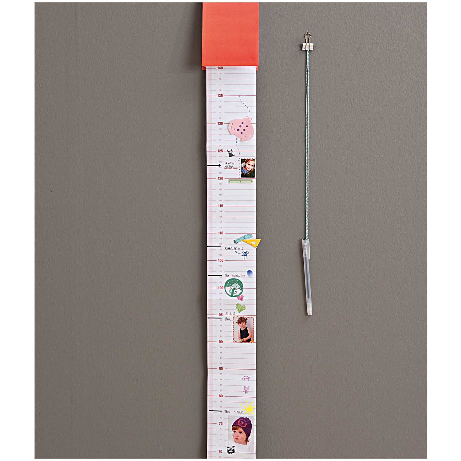 Paper Poetry Foldback Klammern halten eine lange, dekorierte Liste an der Wand. Neben der Liste hängt ein Stift an einer Schnur.