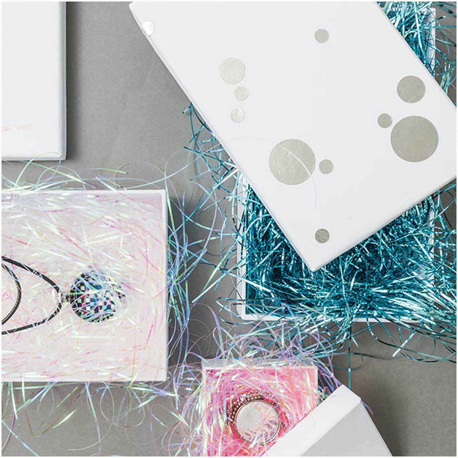 Paper Poetry Füllmaterial Flitter 20g in verschiedenen Geschenkboxen, dekoriert mit glänzendem Flitter von Rico Design.