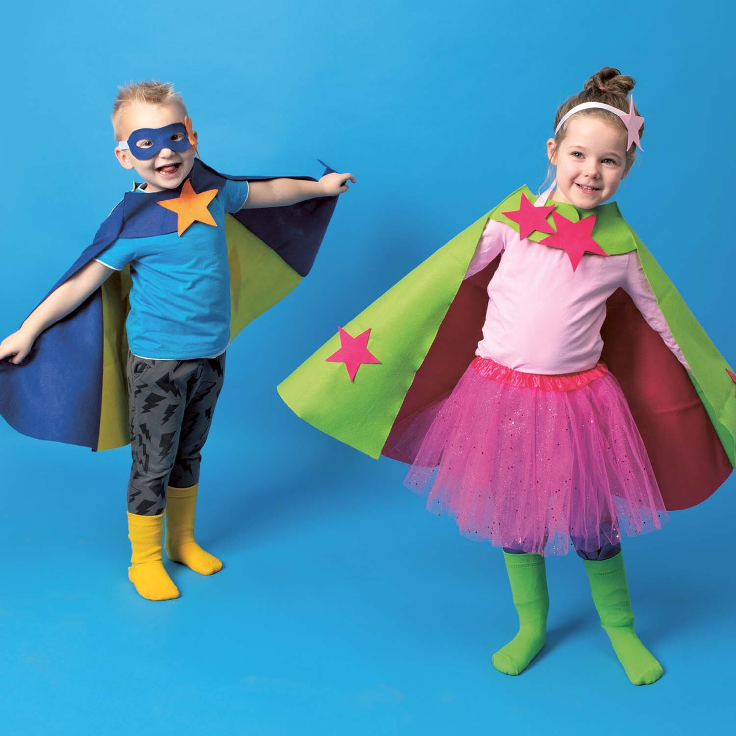 Nähanleitung Superhelden-Kostüm: Zwei Kinder in bunten Superhelden-Kostümen mit Umhängen und Masken.