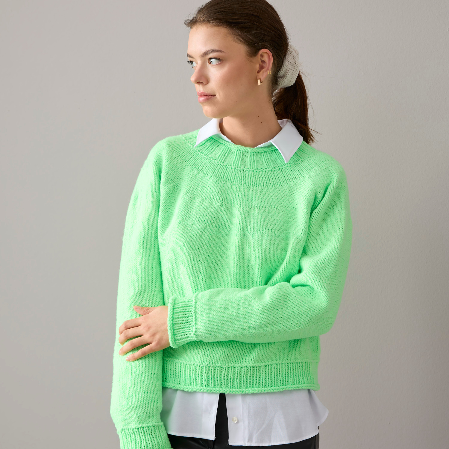 Vegan Cashmere Special: Frau trägt grünen Pullover über weißer Bluse, Rico Design, gemütlich und stilvoll.