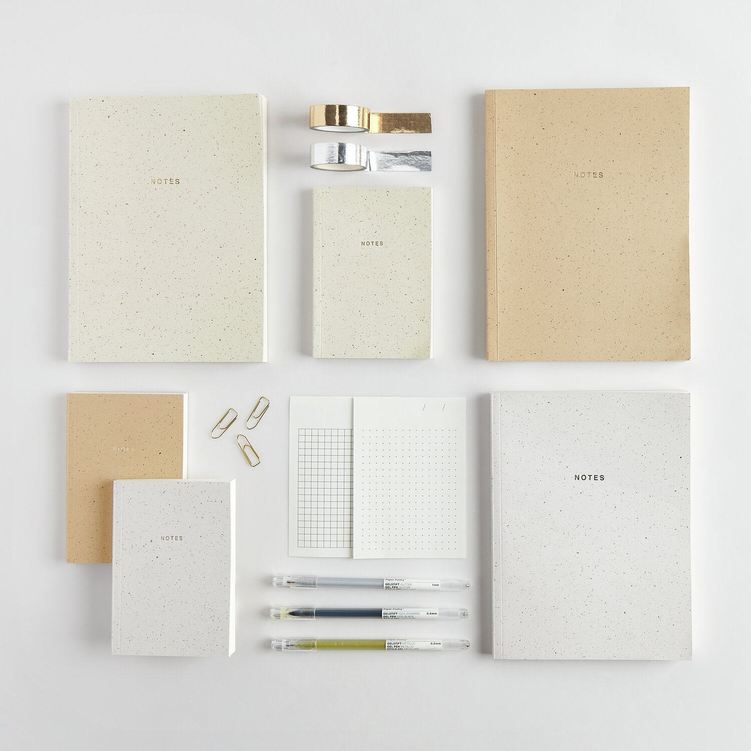 Paper Poetry Notizbuch L und S in verschiedenen Größen und Farben, arrangiert mit Stiften und Clips.