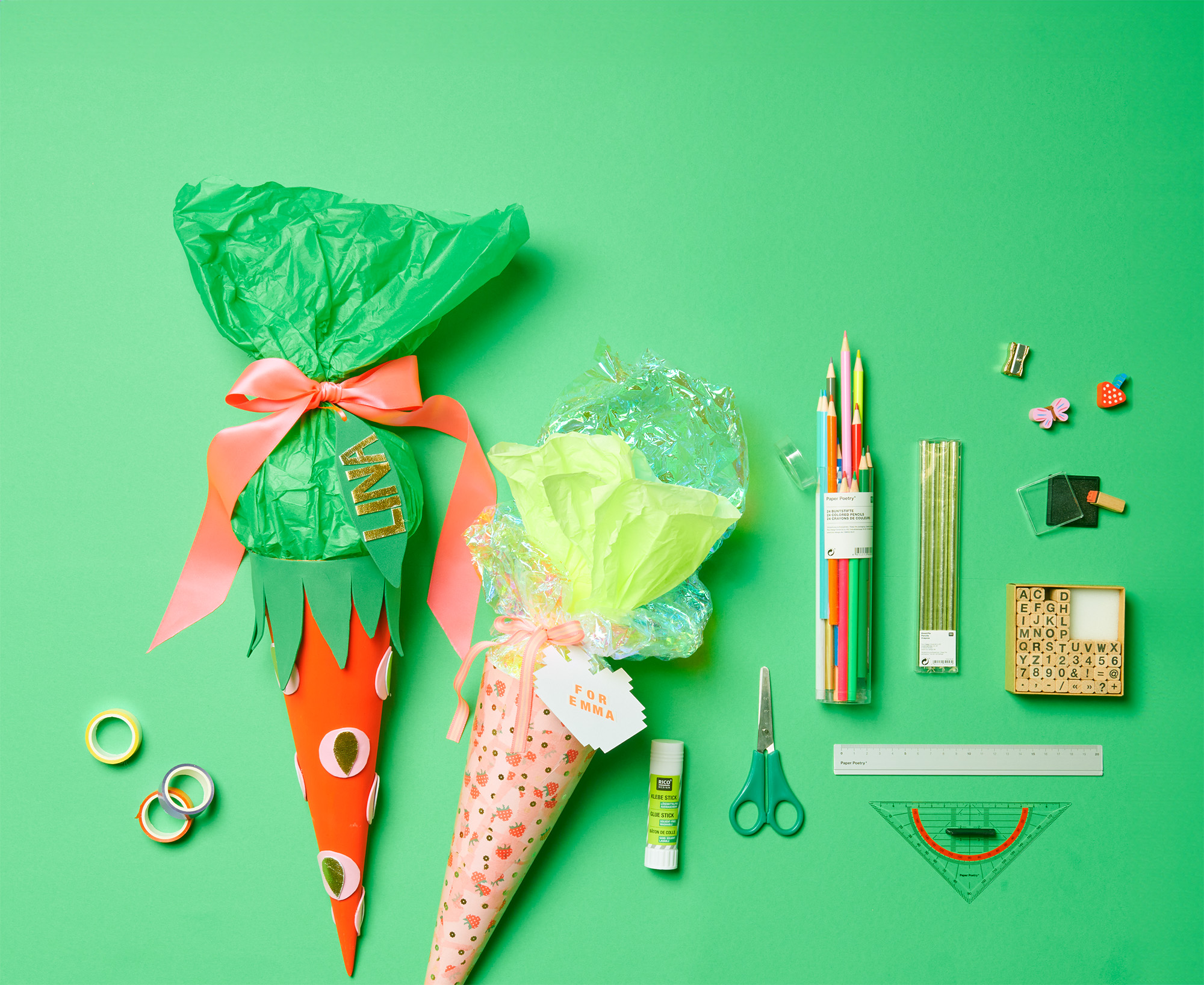 Schultüten in Erdbeer-Design mit Buntstiften, Lineal, Stempel, Radiergummis und bunten Tapes. Flatlay von Produkten.