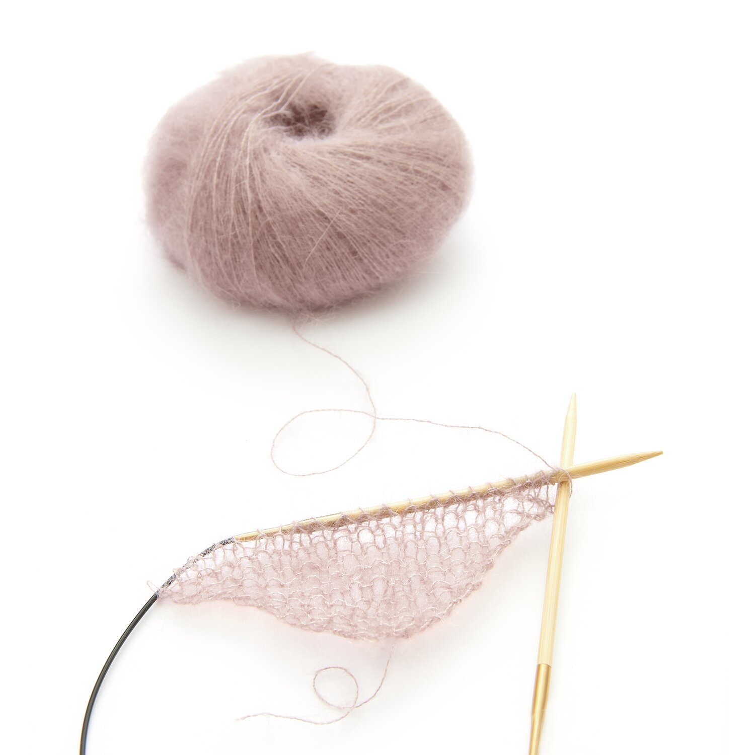 Essentials Super Kid Mohair Loves Silk: Altrosa Garnknäuel von Rico Design mit Stricknadeln und begonnener Strickarbeit.