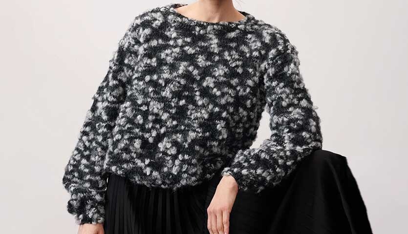 Strickanleitung Pullover aus Fashion Alpaca Vibes: Frau trägt schwarz-weißen, flauschigen Pullover mit langen Ärmeln, ideal für kühle Tage.