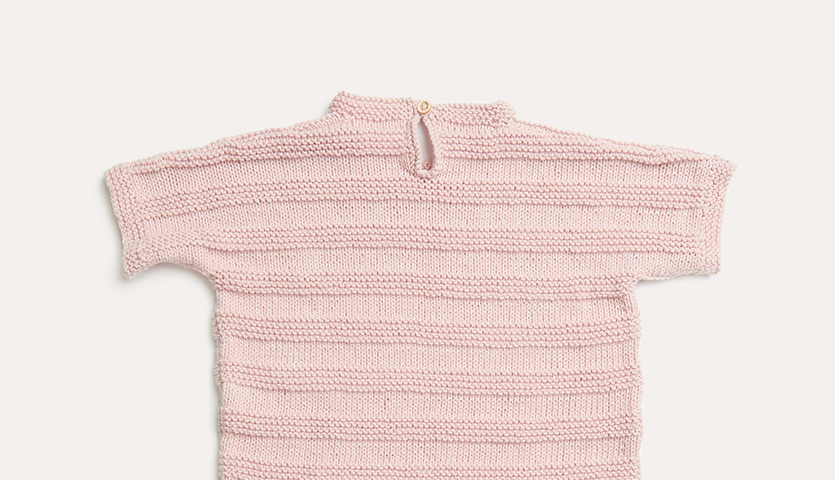Strickanleitung Kleid und Stirnband aus Baby Organic Cotton: Rosa gestricktes Kleid mit kurzen Ärmeln und Knopfverschluss, ideal für Babys.