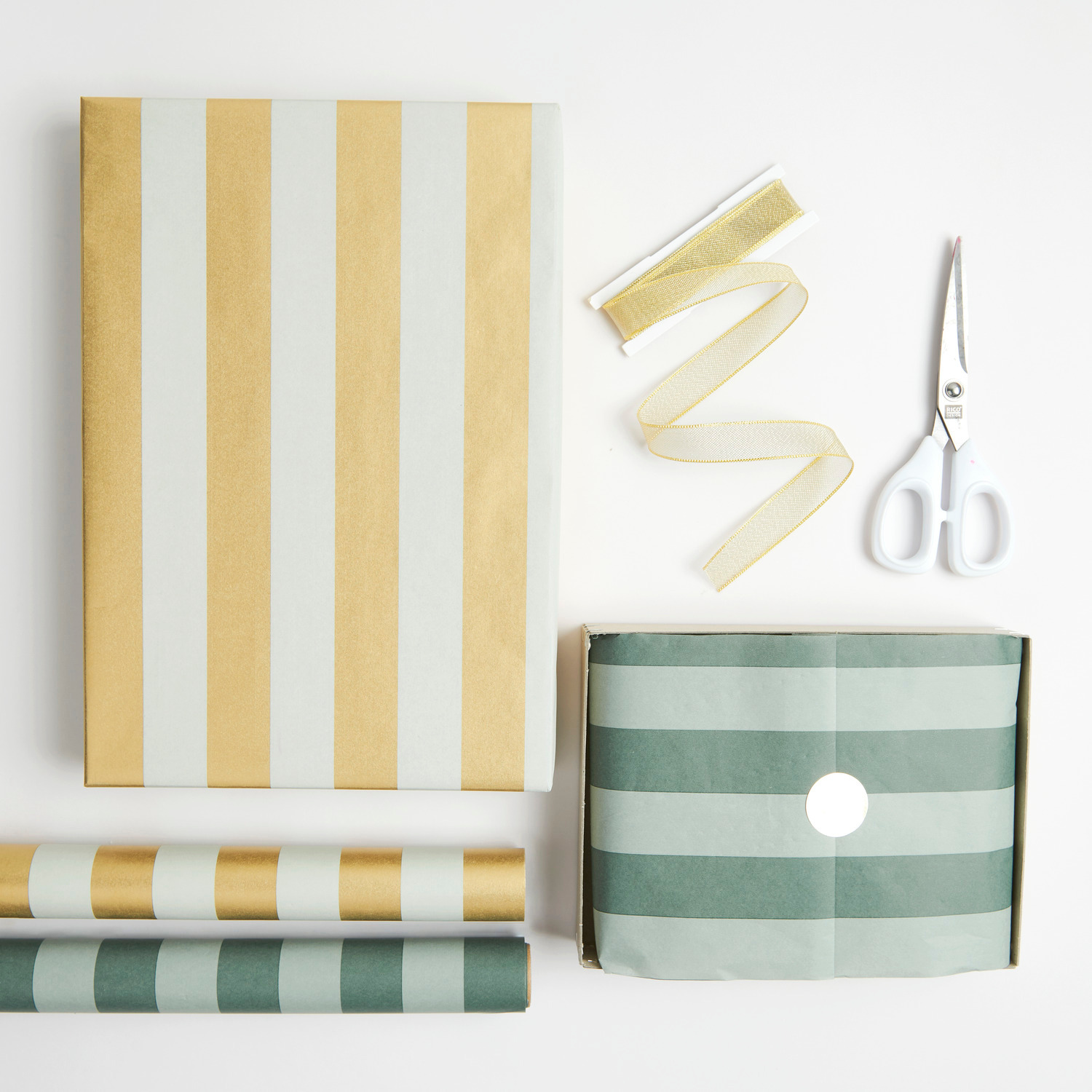 Seidenpapier mit Streifen in Creme/Weiß und Grün, dekoriert mit Schere und Geschenkband. Ideal für kreative Verpackungen.