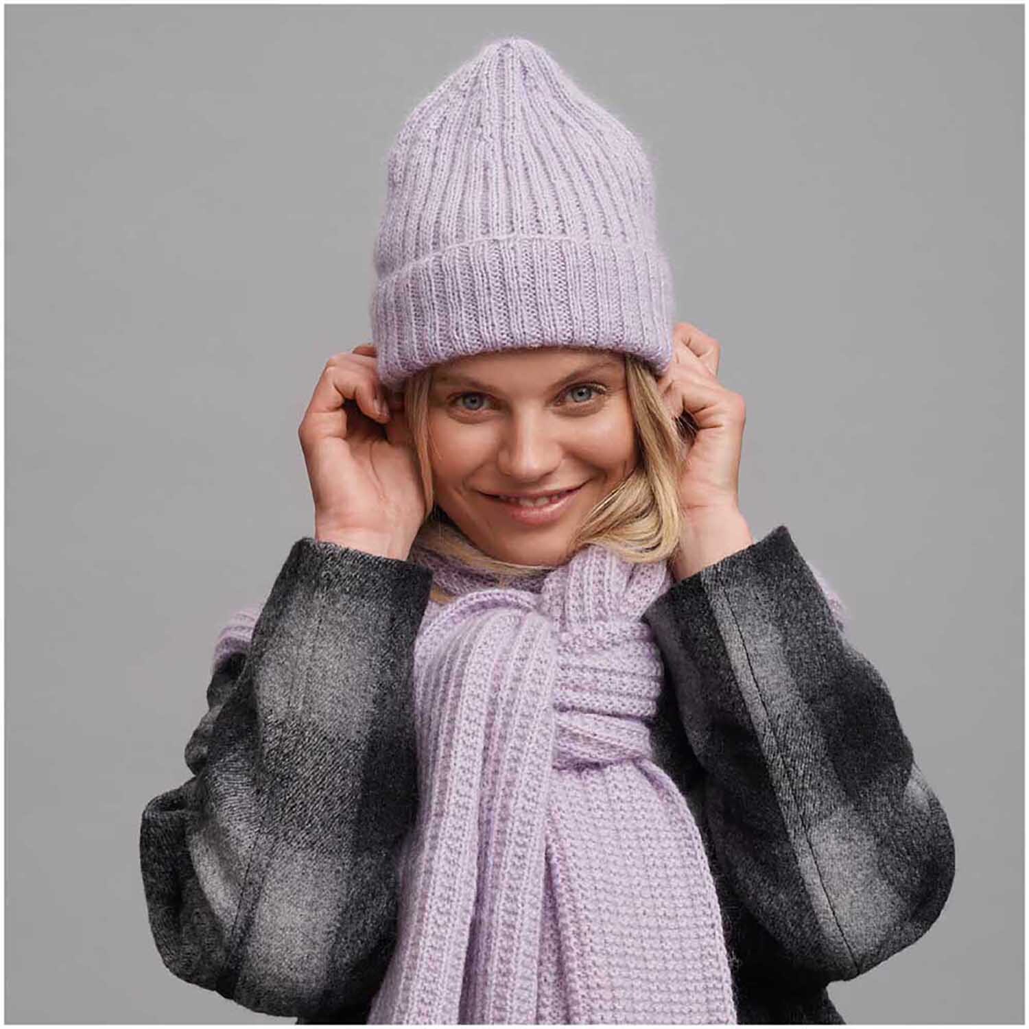 Essentials Super Kid Mohair Loves Silk Strickset Mütze, blasslila, von Rico Design. Frau trägt gestrickte Mütze und Schal.