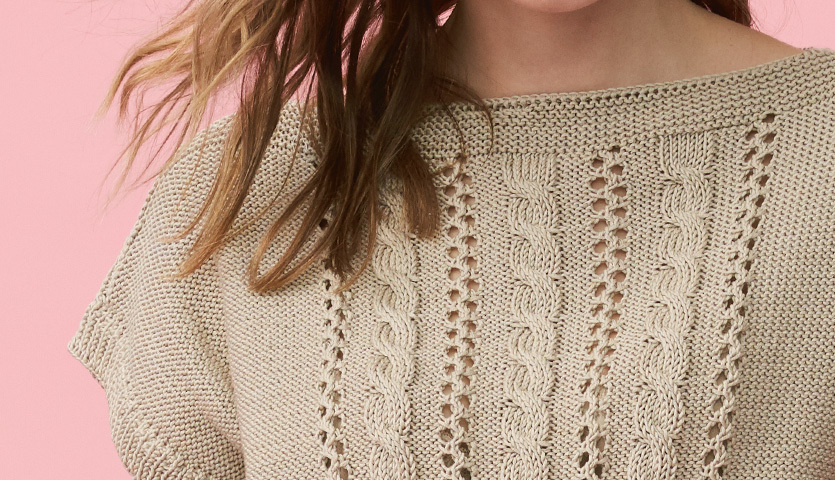 Strickanleitung Leichtes Top aus Mille Fili: Beiges, gestricktes Oberteil mit Zopfmuster vor rosa Hintergrund. Ideal für Sommermode.
