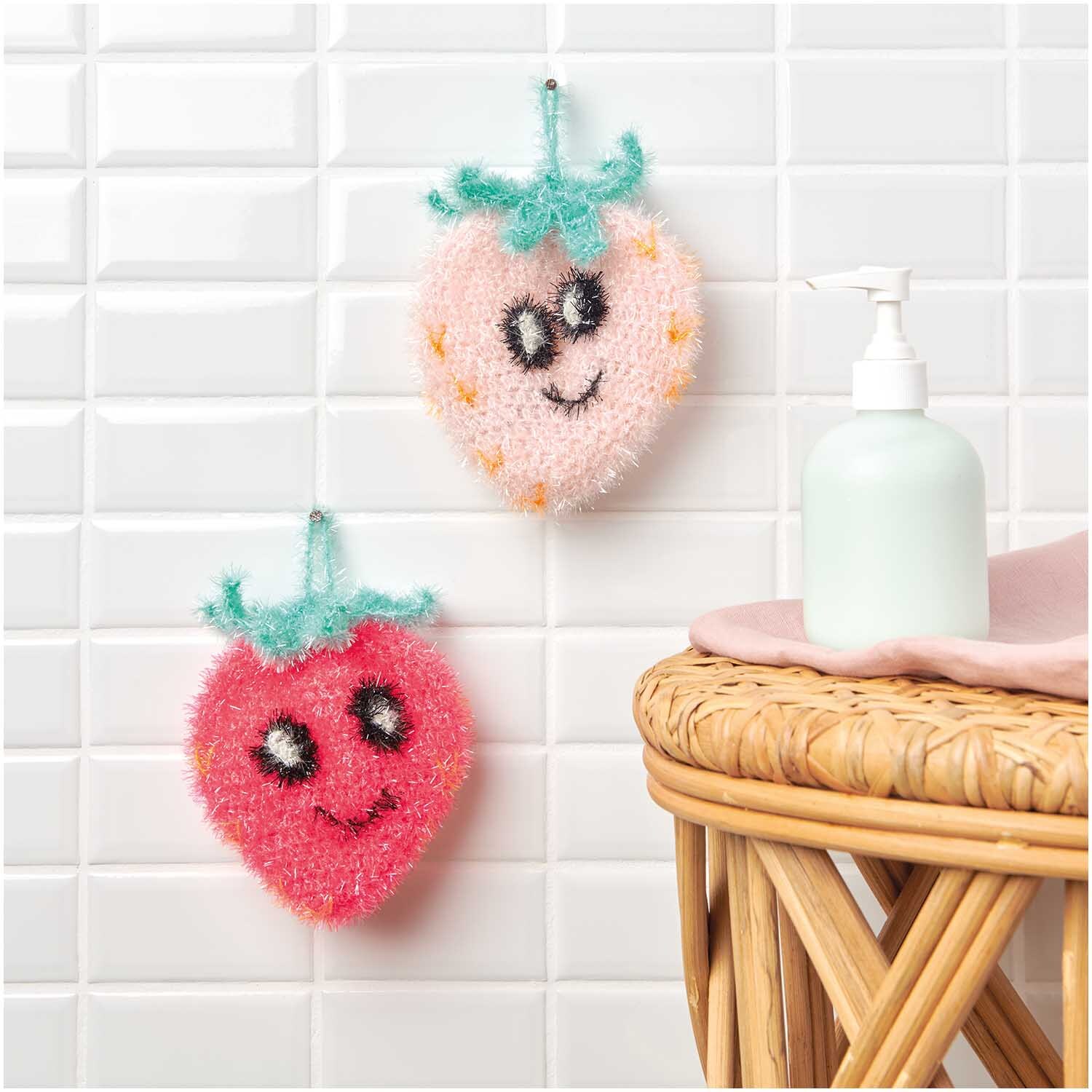 Creative Bubble: Zwei fröhliche Schwämme in Erdbeerform, einer rosa, einer rot, hängen an weißen Fliesen.