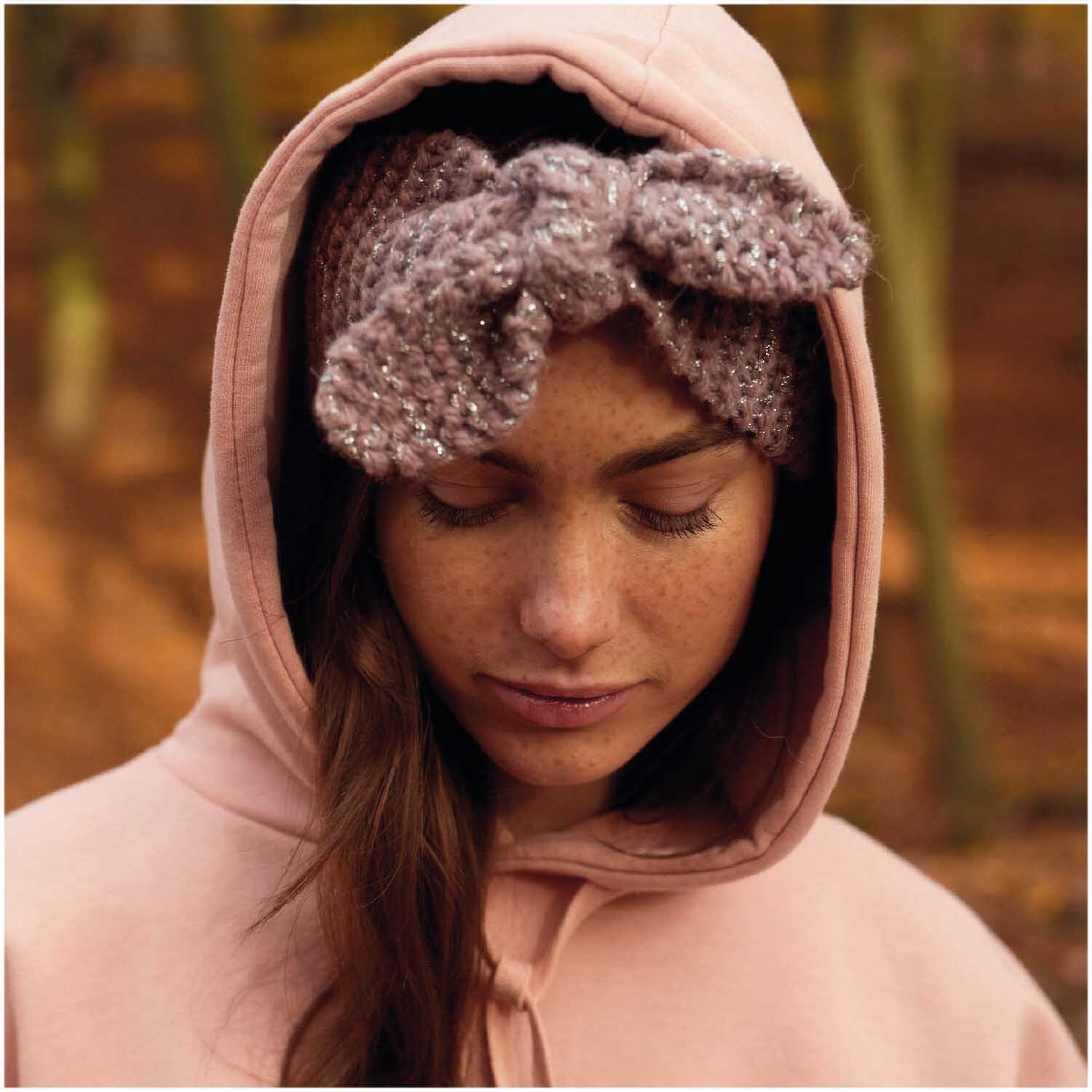 Essentials Alpaca Twist Chunky Stirnband in Mauve von Rico Design, getragen von Frau im Wald.