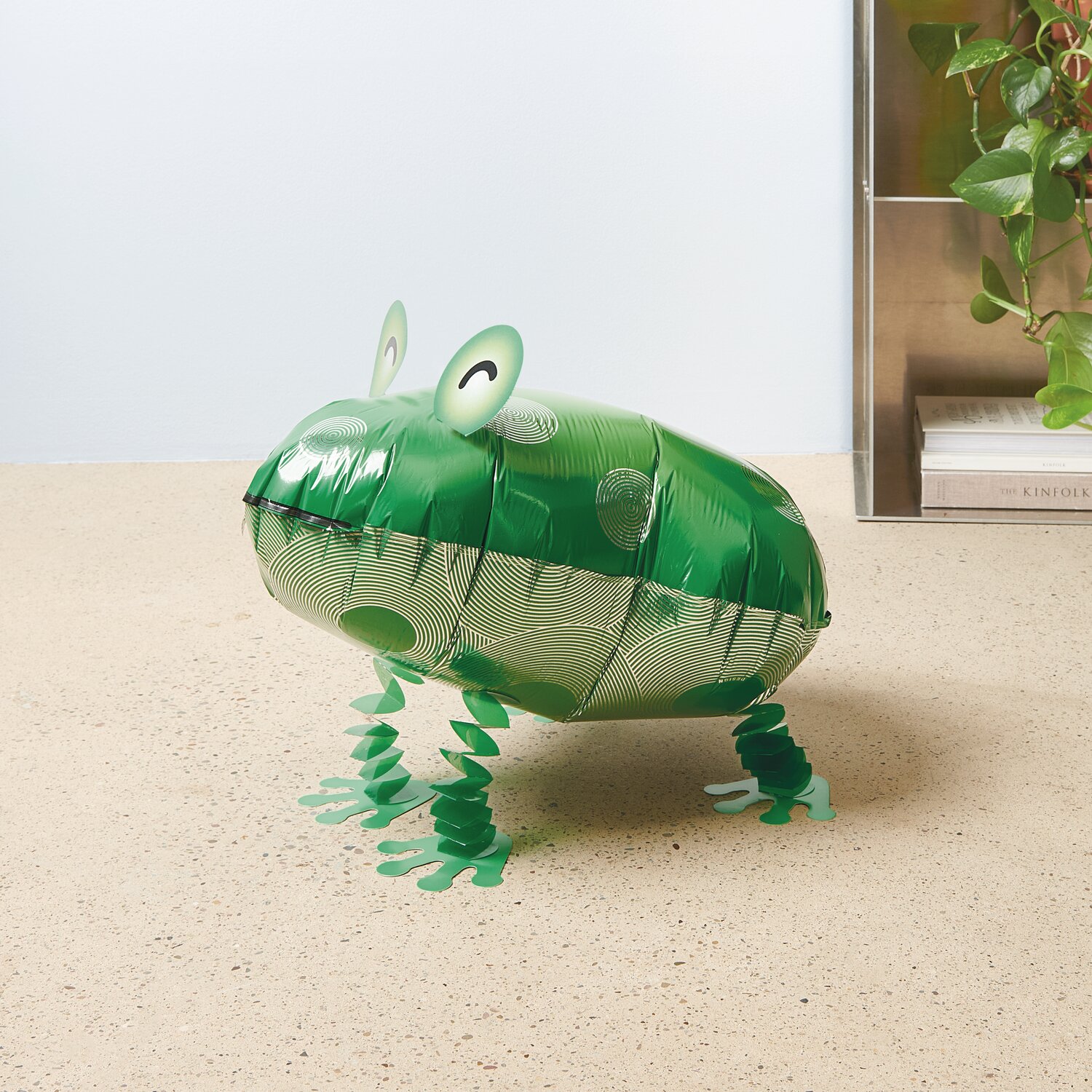 Folienballon Airwalker Frosch in leuchtendem Grün, 41x20x31cm, auf hellem Boden stehend.