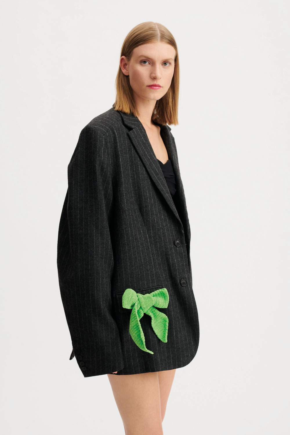 Ricorumi Nilli Nilli Häkelset zeigt eine neon grüne Schleife an einem schwarzen Blazer.