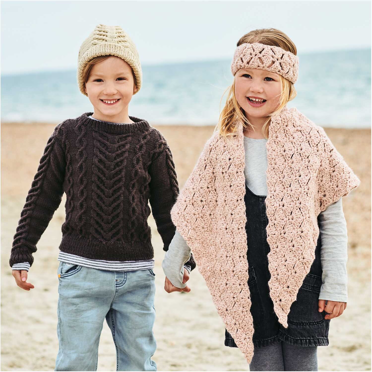 Essentials Super aran: Zwei Kinder am Strand, tragen gestrickte Kleidung in Puder, 50g 100m, von Rico Design.