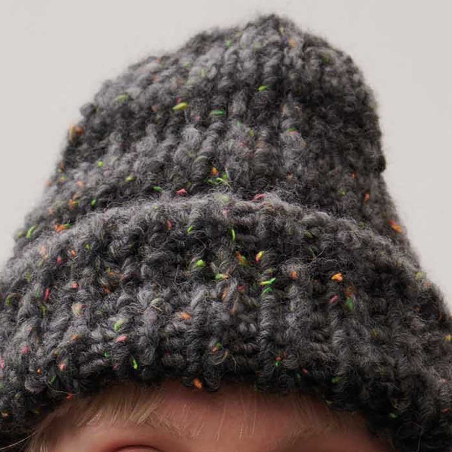 Creative Melange Big Tweed Super Chunky Mütze in Anthrazit von Rico Design, gestrickt mit bunten Akzenten, zeigt eine grobe, warme Textur.