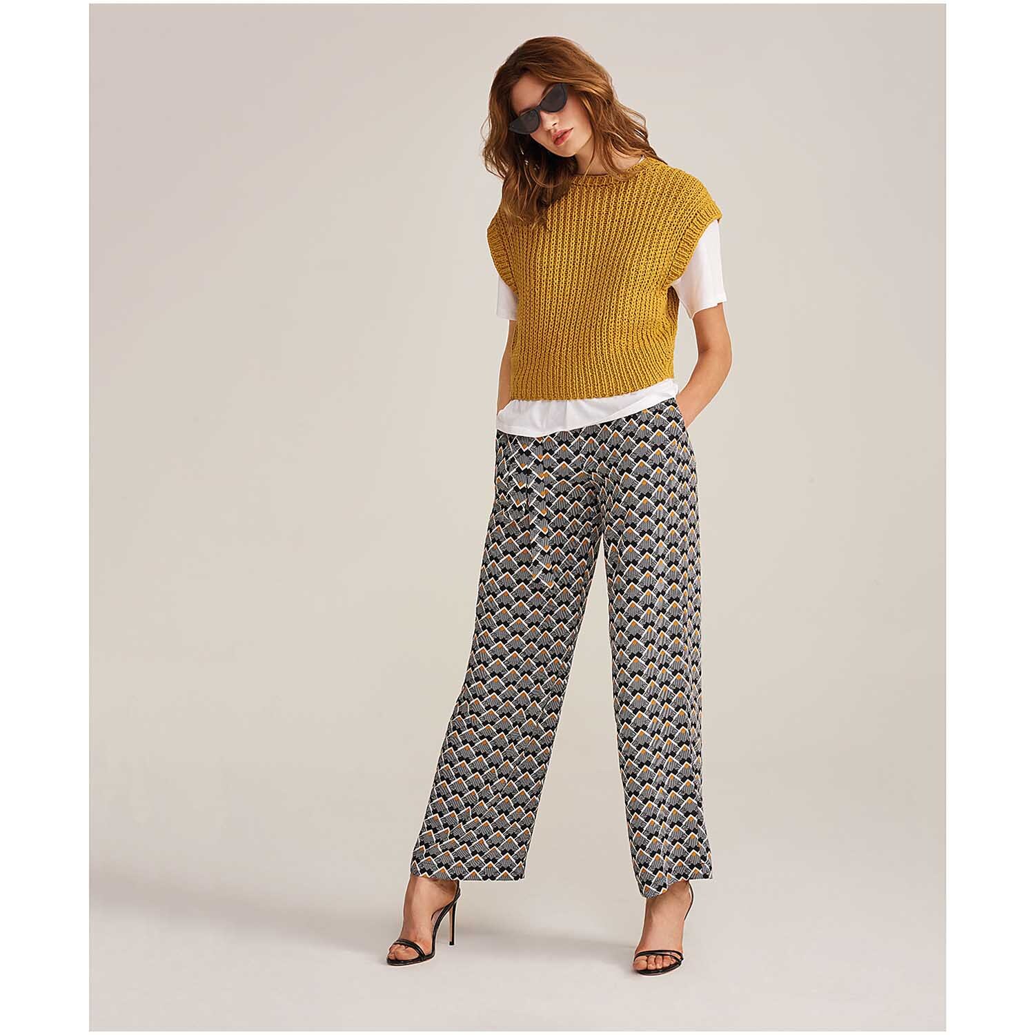 Fashion Linen Swell aran: Frau in senfgelbem Strickoberteil und gemusterten Hosen von Rico Design.