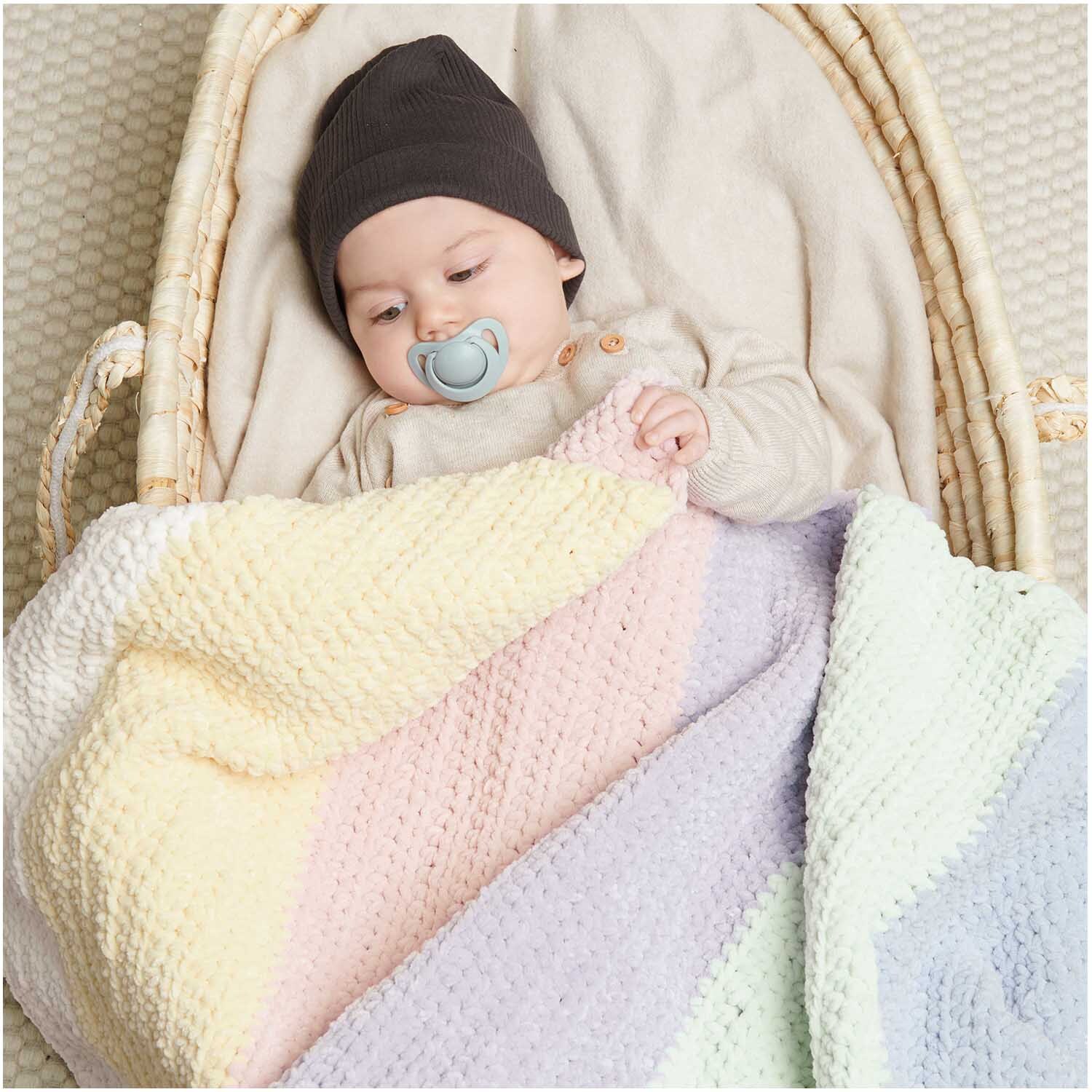 Creative Chenillove: Baby schläft in einem Korb mit bunter Decke aus weichem Garn von Rico Design.