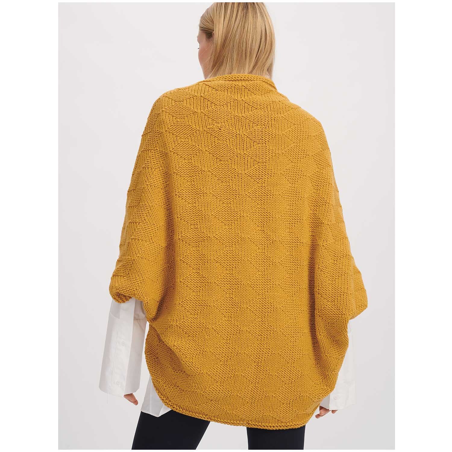 Classik: Frau trägt gestrickten Poncho in Senf, hergestellt von Wolle Rödel, 50g 90m.