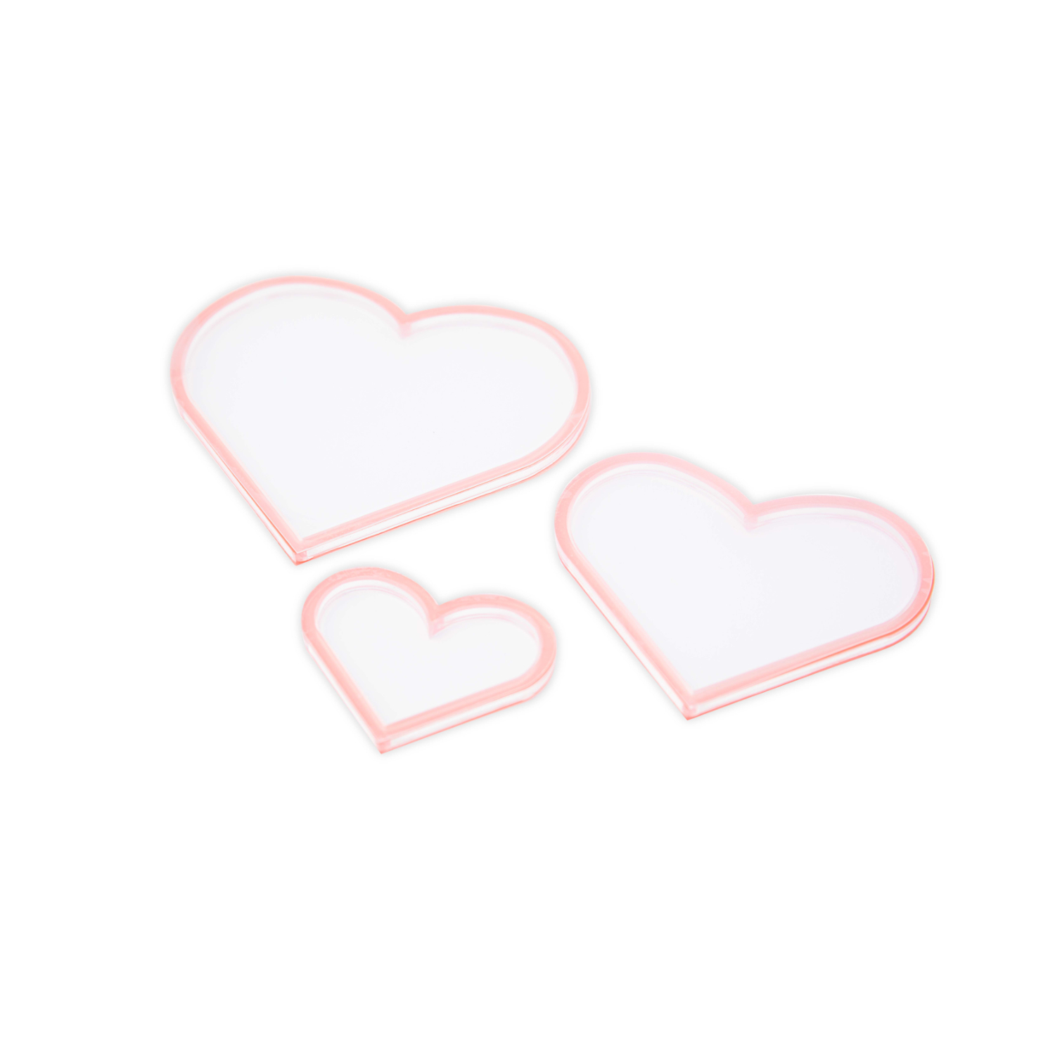 Making Essential Shaker Panes Hearts 3PK: Drei herzförmige, rosa-umrandete Schablonen von Sizzix auf weißem Hintergrund.