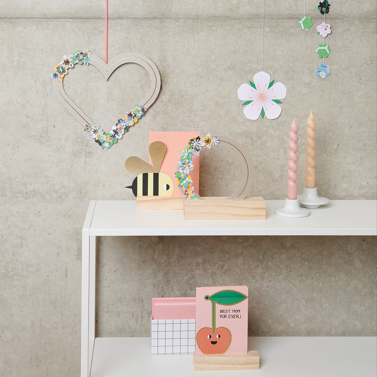 Bastelanleitung 3D Papier-Blumenkranz: Dekorativer Tisch mit buntem Blumenkranz, Kerzen und Bastelmaterialien.