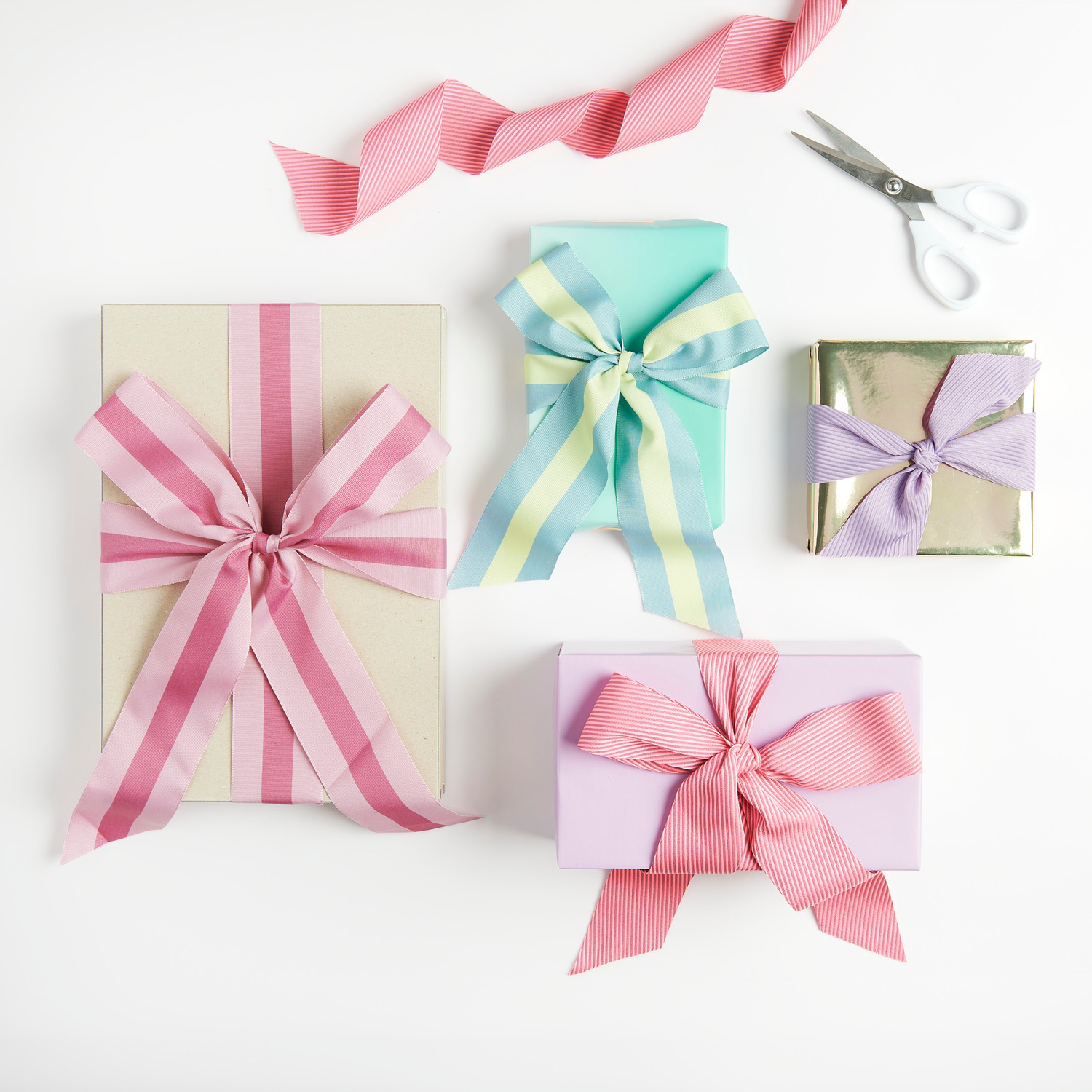 Webband Streifen Altrosa/Violett: Geschenkverpackungen mit farbigen Bändern, Schere im Hintergrund.