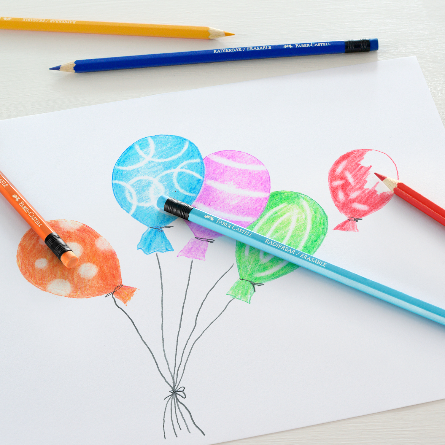 Classic Colours radierbarer Buntstift-Set von Faber Castell, 12 Stück, zeigt bunte Ballons auf Papier.