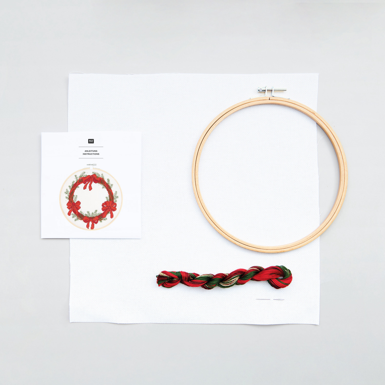 Stickpackung Bild Kranz mit Schleifen von Rico Design: Stickrahmen, Garn und Anleitung auf weißem Hintergrund. Ideal für kreative Handarbeiten.