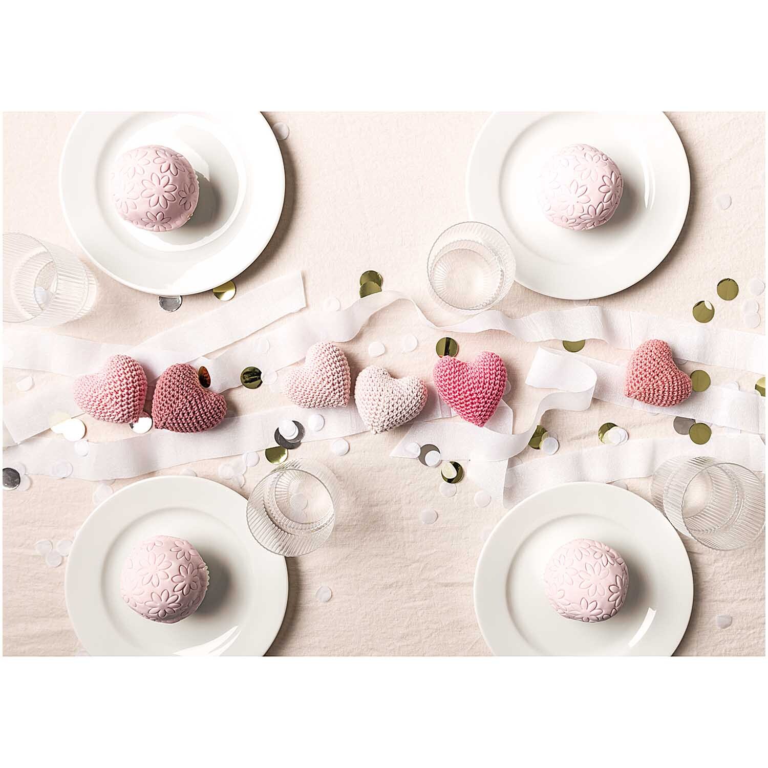 Creative Ricorumi dk: Tischdekoration mit gehäkelten Herzen in Rosa, umgeben von Geschirr und Gläsern, ideal für festliche Anlässe.