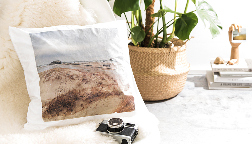 Bastelanleitung Fototransfer auf Stoff: Kissen mit Strandmotiv, umgeben von Pflanzen und Kamera.