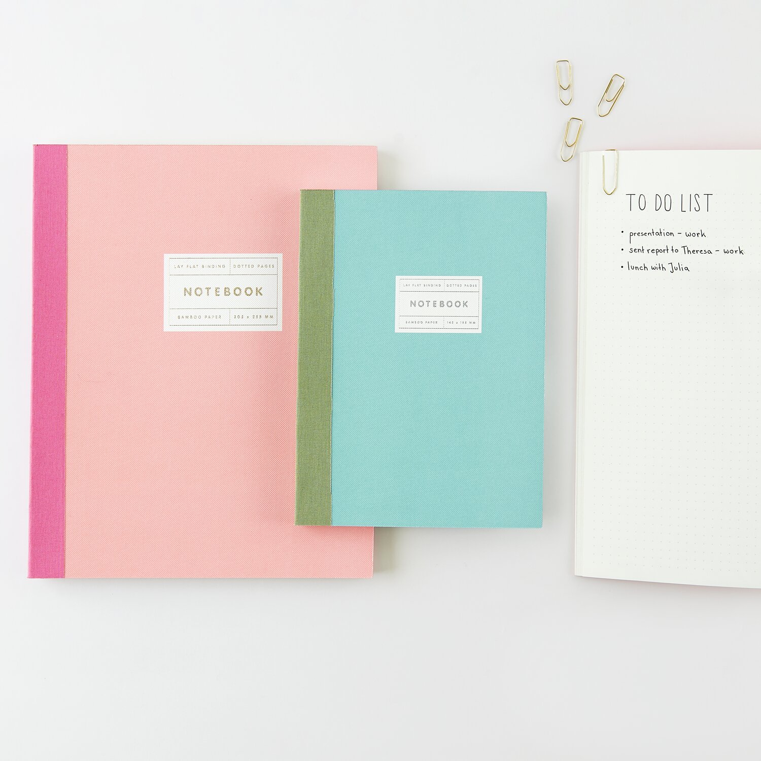 Paper Poetry Notizbuch L und S in Koralle und Mint mit Goldrand von Rico Design, auf einem Tisch mit Büroklammern.