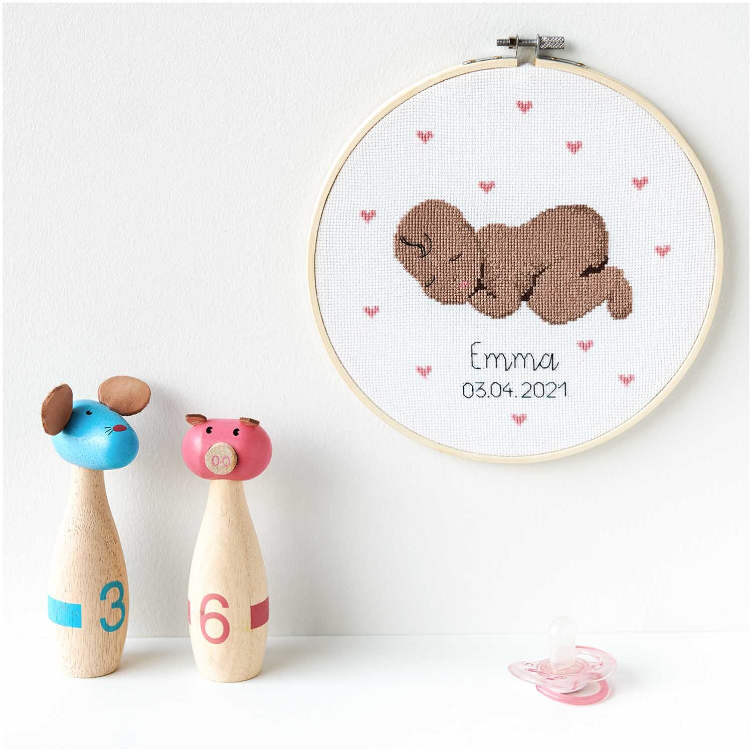 Figurico Stickpackung Baby 20cm zeigt ein schlafendes Baby in Braun mit rosa Herzen auf weißem Hintergrund.