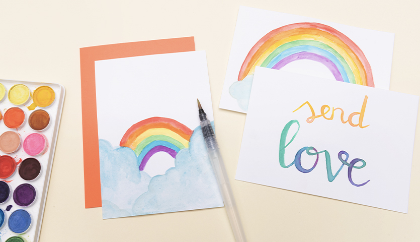 Anleitung kunterbunte Postkarten mit Aquarellfarben gestalten: Regenbogenmotive und "send love"-Schriftzug auf Karten mit Farbpalette.